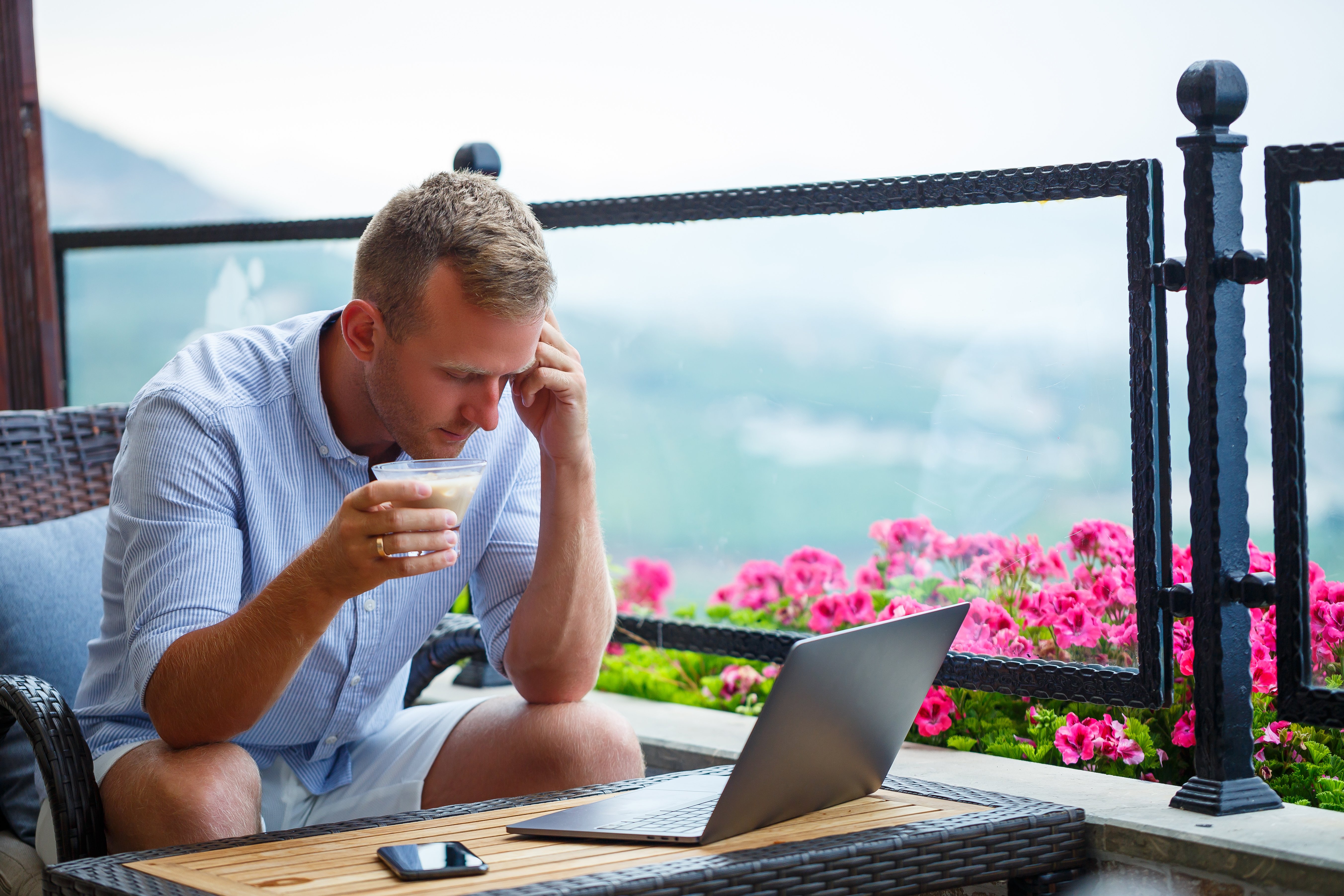 male-businessman-working-laptop-rooftop-cafe-with-beautiful-panoramic-view-guy-blogger-drinks-coffee-works-computer-while-traveling